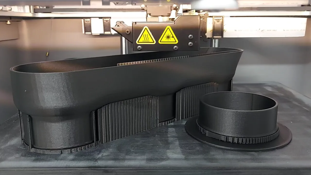 Black FDM-printed functional polymer components on a build plate